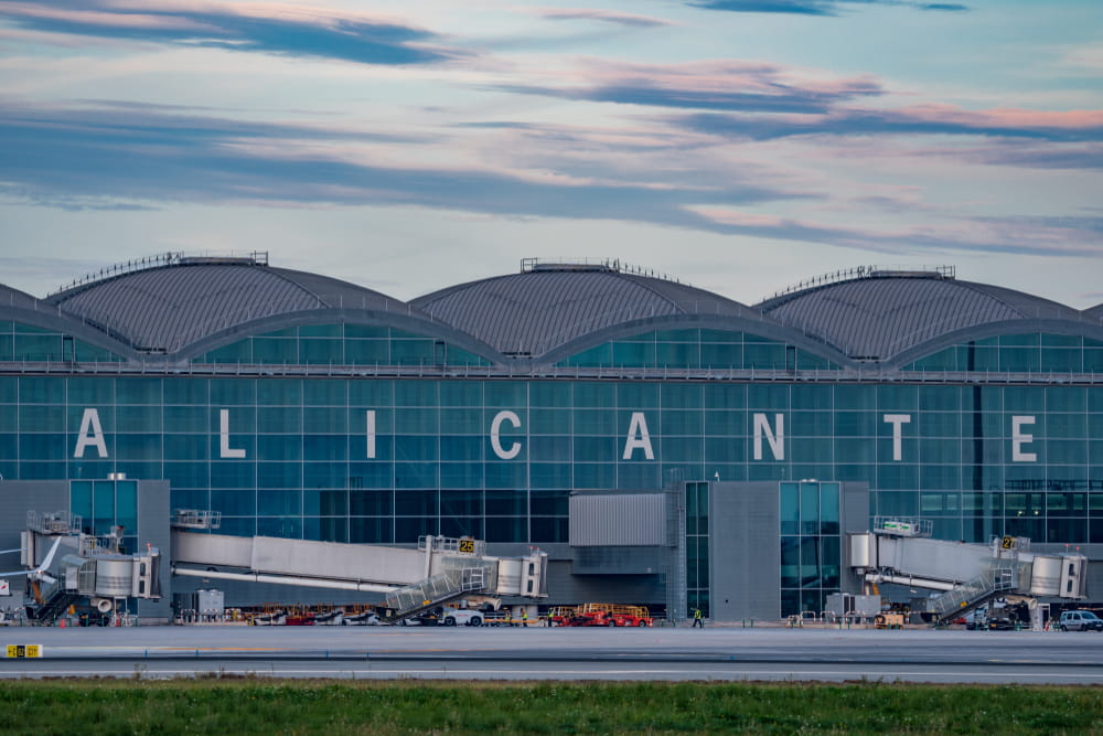 Alicante Airport terminal building at sunset with jet bridges and runway view