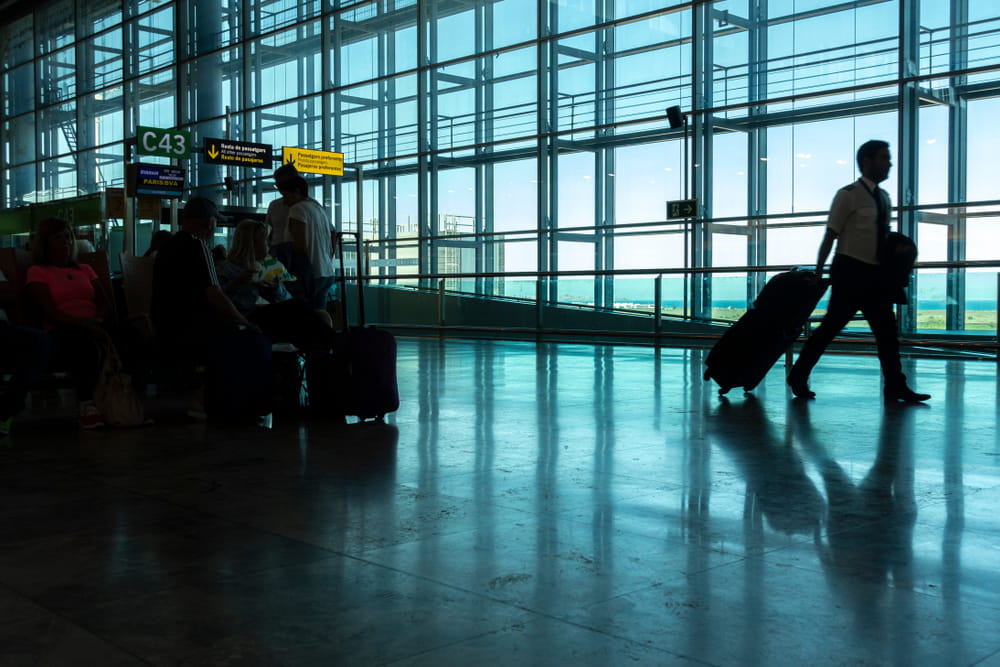 Passengers waiting near gate C43 at Alicante Airport with glass windows and runway views