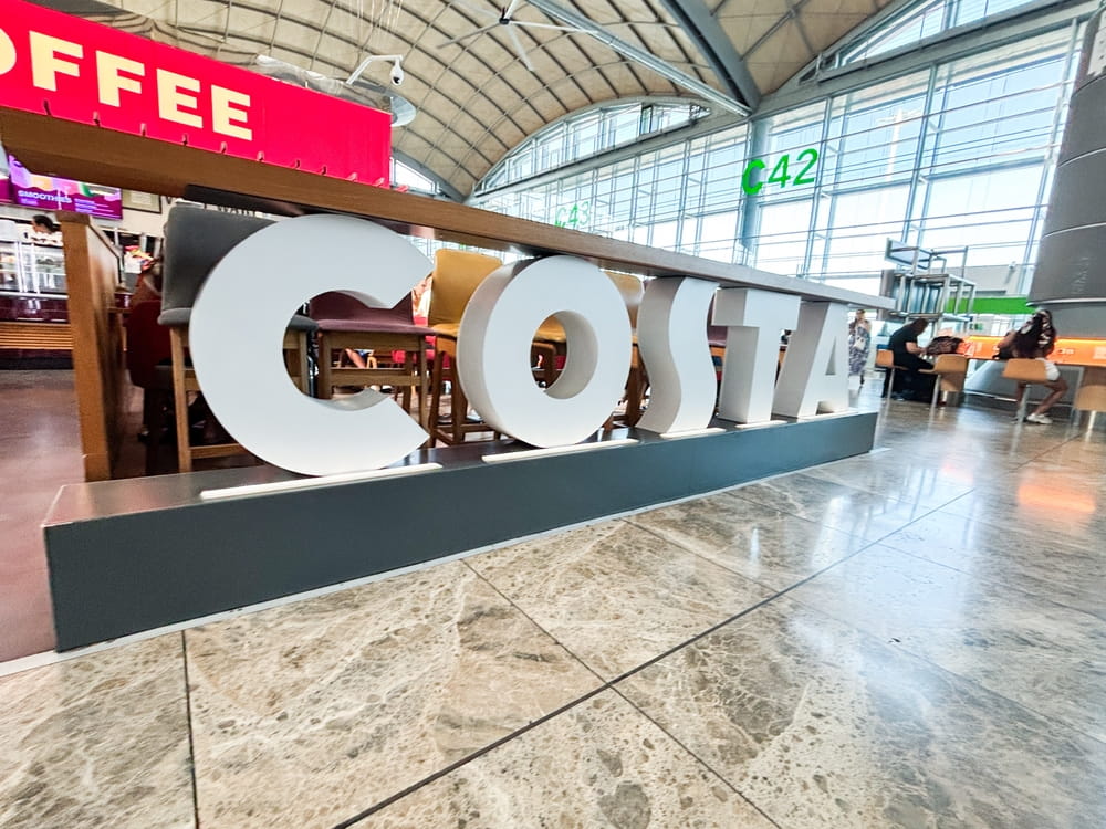 Costa Coffee area inside Alicante Airport near gate C42 with passengers and terminal seating