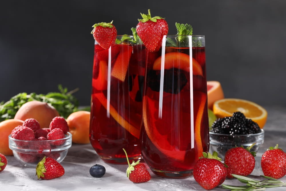 Copas altas de sangría roja en España con fresas, rodajas de cítricos, frutos rojos y menta