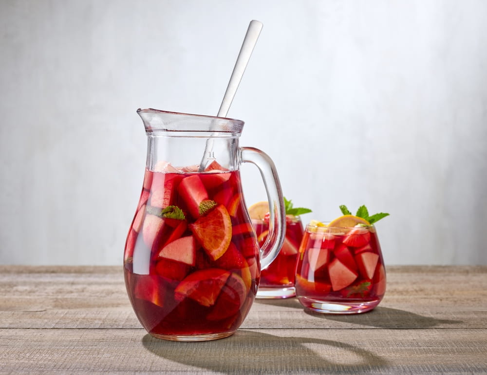 Sangria in Spain: Jug and glasses of red sangria with fresh fruit and mint on a wooden table